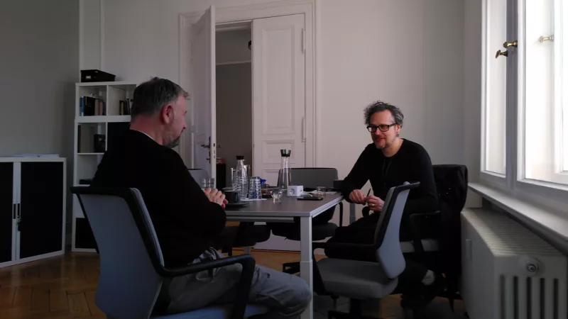 Holger Bergmann und Falk Schreiber sitzen sich an einem Tisch gegenüber.