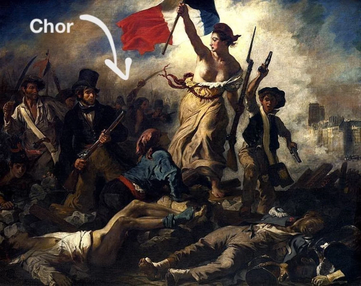 Ein Gemälde zeigt die französischen Revolution. Am Boden liegen tote und verletzte Menschen, über denen eine barbusige Frau die französische Flagge schwenkt. Hinter ihr stehen bewaffnete Männer. Auf diese ist ein Pfeil gerichtet, der mit „Chor“ beschriftet ist.