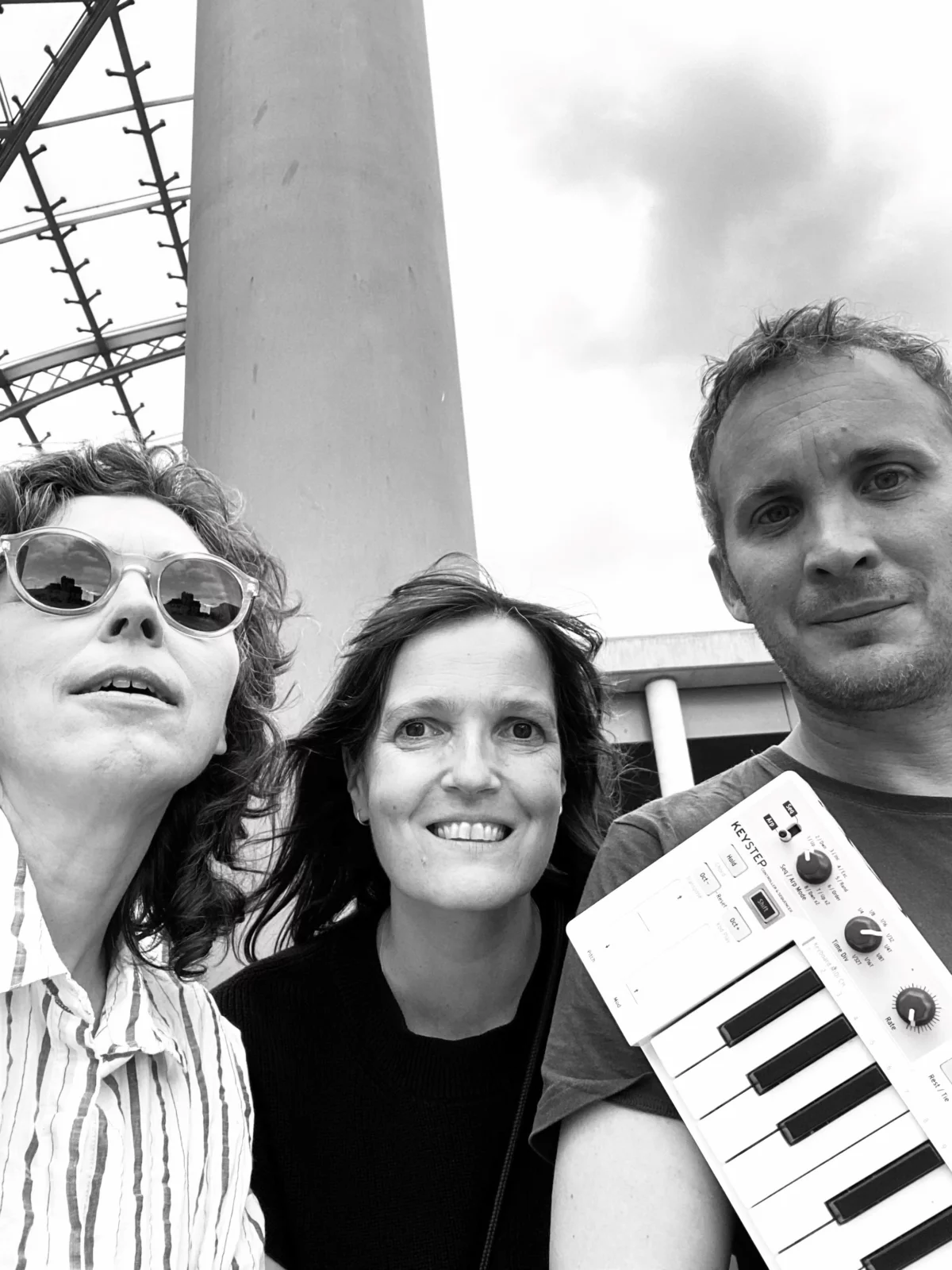 Schwarz-weiß Foto von den Künstlerinnen SE Struck und Alexandra Knieps gemeinsam mit dem Musiker Philip Zoubek, der ein Keyboard vor sich hält.