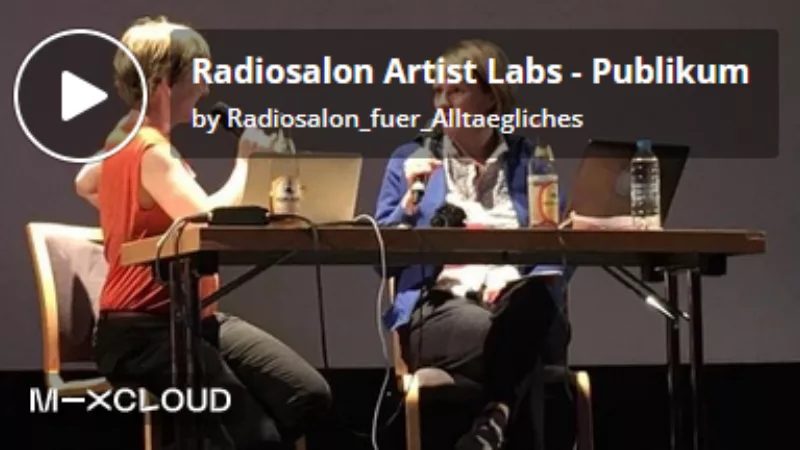Screenshot eines Players. Im Hintergrund zwei Personen, die an einem Tisch sitzen, Mikrofone in der Hand haben und einander zugewandt miteinander sprechen. Darauf liegt die Überschrift „Radiosalon Artist Labs – Publikum“.