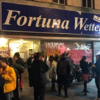 Eine Gruppe von Menschen stehen vor einem Lokal mit dem Namen "Fortuna Wetten".