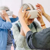 Zwei ältere Menschen tragen eine VR-Brille.
