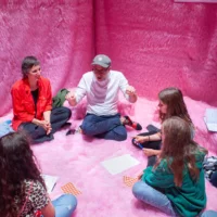 A small group of people with children are sitting in a plush pink room.