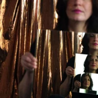 A woman holds a mirror in front of her chest. Her face is reflected in it four times.