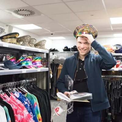 A person wears a very colorful hat in a clothing store.