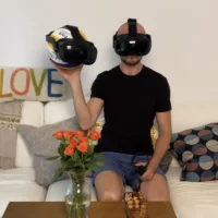 Mann mit VR Brille sitzt auf einem weißem Sofa.