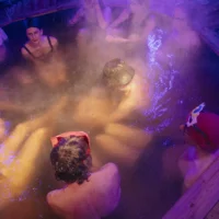 A group of people sit in a whirlpool at night.