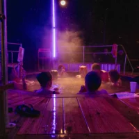 A group of people sit in a whirlpool at night.