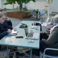 A group of people is sitting at a table with laptops.