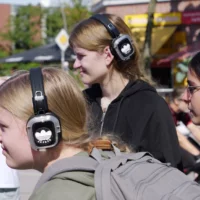 Zu sehen sind vier Menschen in Nahaufnahme, die Kopfhörer tragen.