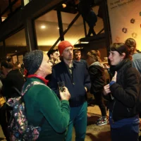 Vor der abendlichen Front der Berliner Festspiele stehen Menschengruppen ins Gespräch vertieft.