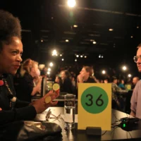 Zwei Menschen sitzen einander an einem Tisch mit der Nummer 36 zum Gespräch gegenüber.