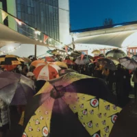 Auf dem Vorplatz von Kampnagel stehen viele Menschen mit aufgespannten Regenschirmen in der Hand.