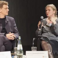Redebeitrag von Mieke Matzke (SheShePop) bei einem Podiumsgespräch, in der Hand das Mikrofon. Neben ihr sitzt ihr zugewandt Thomas Oberender.