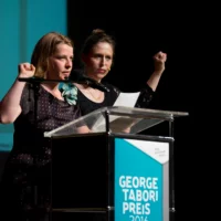 Britta Steffenhagen and Julia von Schacky moderate the evening at the lectern: while they speak, they have their hands clenched into fists.