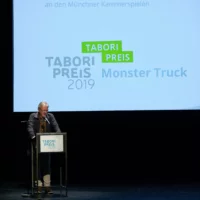 Christoph Gurk hält die Laudatio für die Tabori-Preisträger*innen von Monser Truck auf der Bühne des HAU 1.