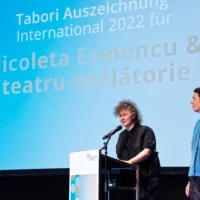 Nicoleta Esinencu und ihre Dramaturgin bei ihrer Dankesrede zur Tabori Auszeichnung International am Redner*innenpult.