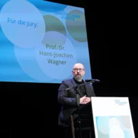 Prof. Dr. Hans-Joachim Wagner verliest am Redner*innenpult eine Jurybegründung.
