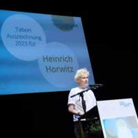 Henrich Horwitz steht am Redner*innenpult und bedankt sich für die Auszeichnung.
