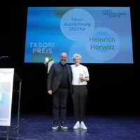 Portrait von Heinrich Horwitz zusammen mit dem Juror Prof. Dr. Hans-Joachim Wagner auf der Bühne. Beide blicken in die Kamera.