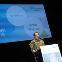 Anna Wagner verliest am Redner*innenpult die Jurybegründung im Rahmen der Preisverleihung.